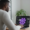 Homme regardant un ordinateur portable affichant une icône néon violette de hashtag sur un fond sombre. L'utilisateur semble analyser les données et l'algorithme d'Instagram pour optimiser sa stratégie de marketing digital en 2025.